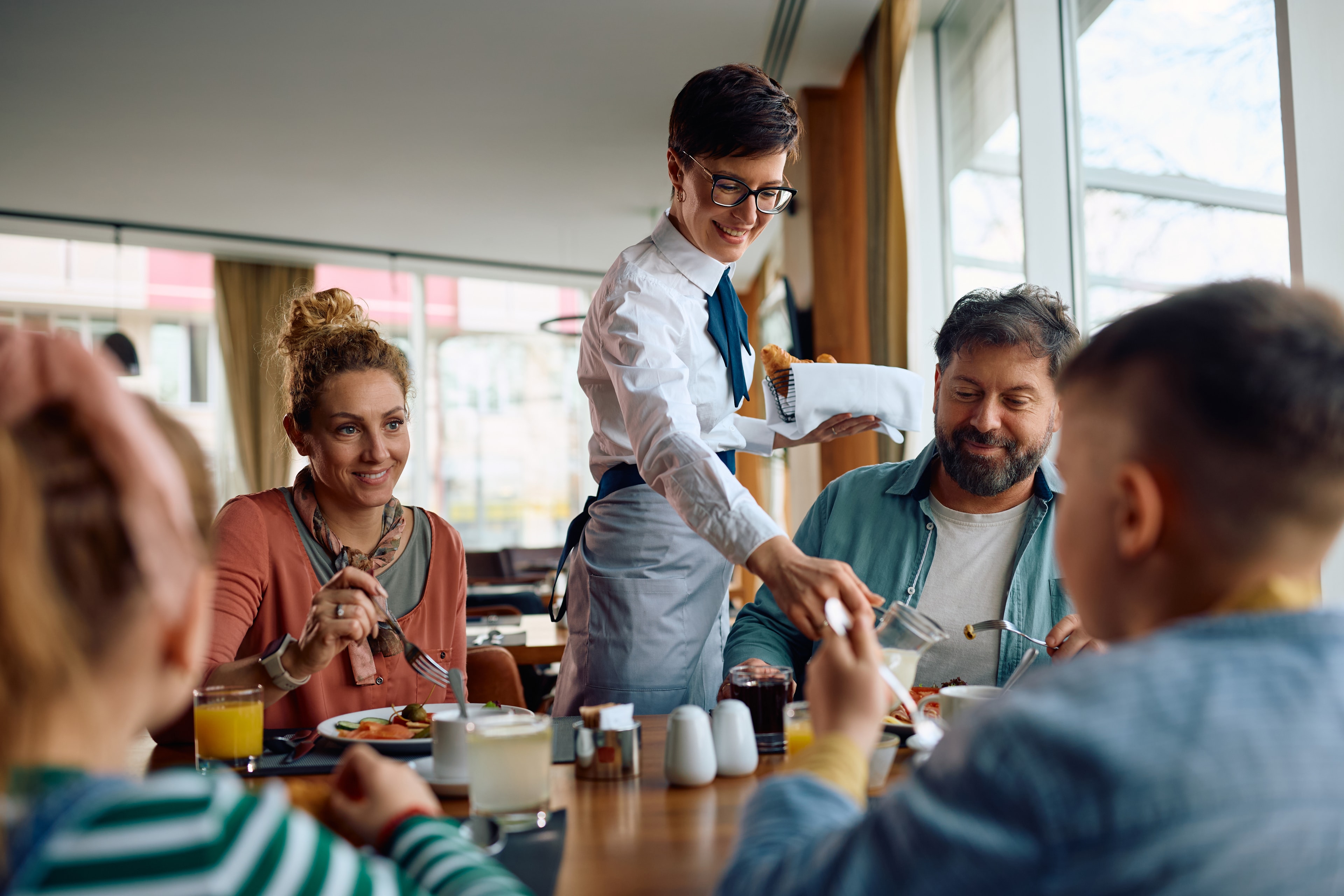 happy-hotel-waitress-serving-family-who-is-having-2026-01-07-02-28-46-utc.jpg